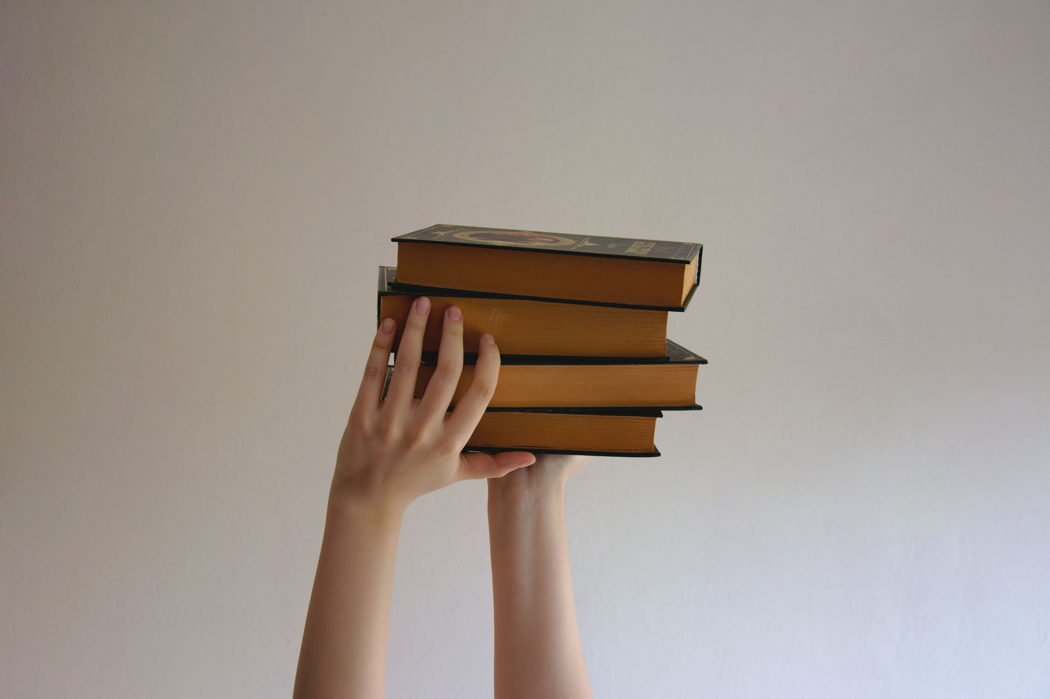 Due mani sollevano una pila di libri