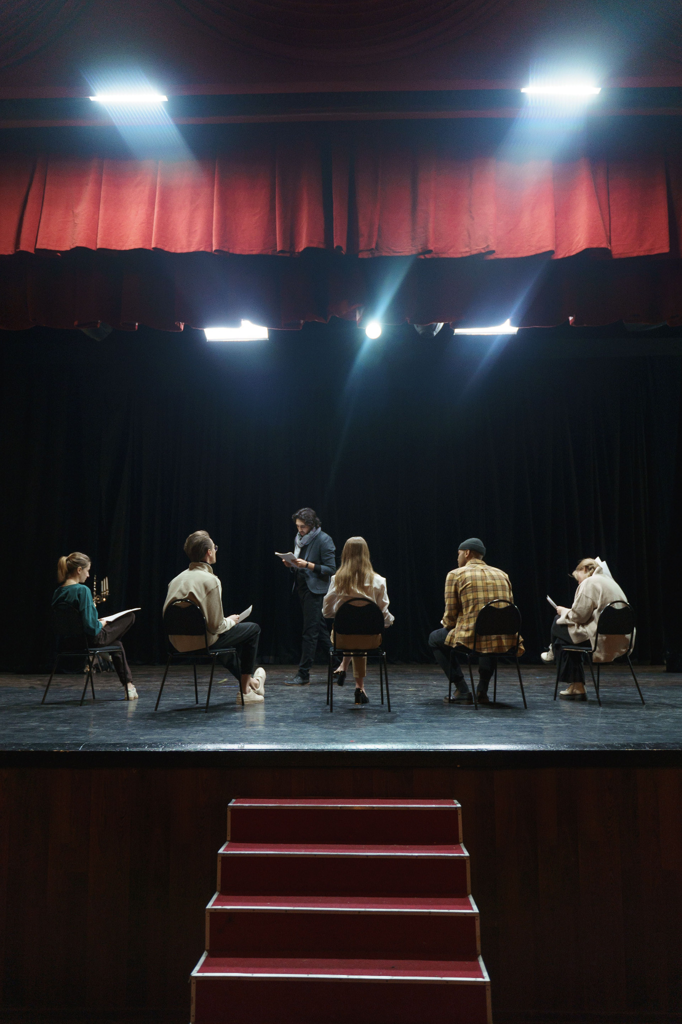 Un gruppo durante una prova teatrale, con una persona in piedi che legge un testo